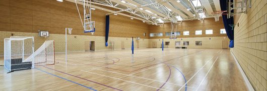 Cheltenham Ladies College gymnasium interior featuring wooden floors, brick and wooden walls, and skylights