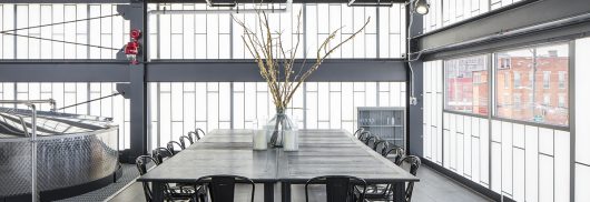 Kalwall facade application at Middle West Spirits showcased in office building with tables, chairs and industrial equipment